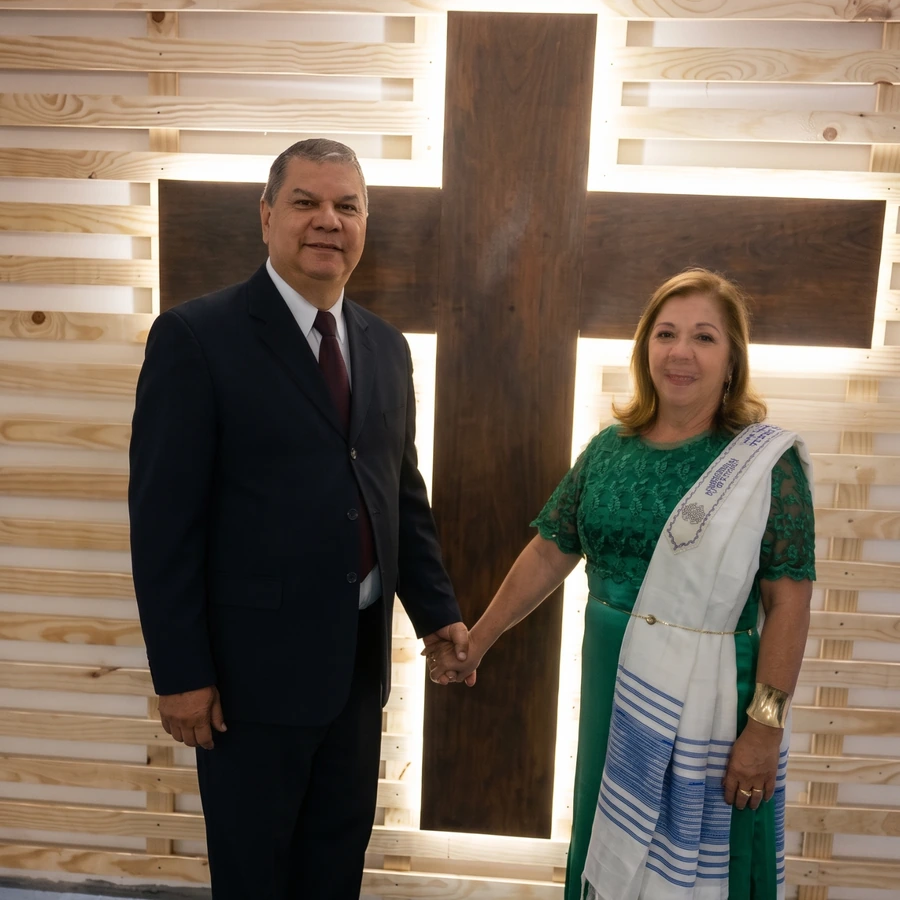 Apóstolos Gelson Gonçalves e Angela Maria T. Gonçalves diante de uma cruz iluminada