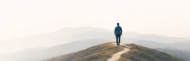 Pessoa caminhando por uma trilha entre montanhas, representando uma jornada de crescimento